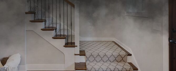 Staircase with patterned carpet and dark wooden steps, adjacent to a wall potentially suitable for home elevators installation.