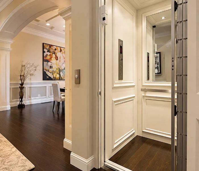 home elevator Elegant home interior with a white-paneled home elevator. Art on wall, dark wood floor, and arched entryway enhance the sophisticated design.